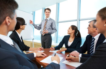 Photo of successful businessman reading lecture to his colleagues at presentation of new project